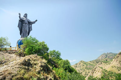 Statue on landscape against clear blue sky