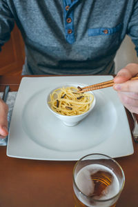 Midsection of man having noodles and worms in restaurant