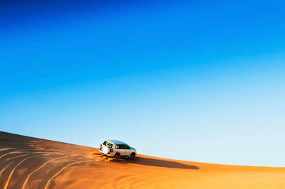 Tractor on desert against clear blue sky