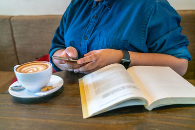 Man holding coffee cup and book