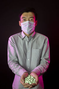 Portrait of young man standing against black background