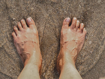 Low section of man standing on sand