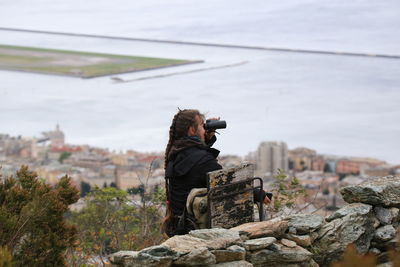 Rear view of man photographing on rock