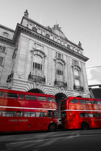 Red cars on street in city against sky