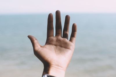 Close-up of hand against sea