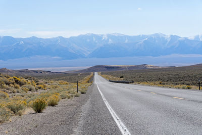 Road leading towards mountains against sky