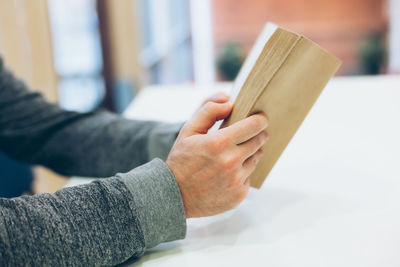 Midsection of man holding book