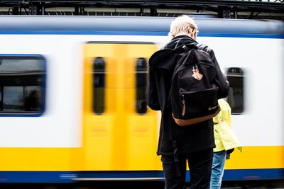 Rear view of men standing by train at railroad station platform