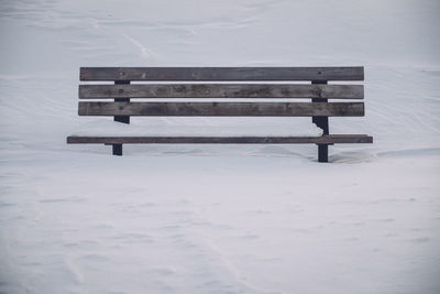 Close-up of bench on snow covered landscape