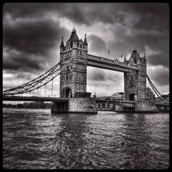 Bridge over river against cloudy sky