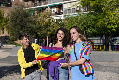 Young diverse friends walking on the street with the lgbt rainbow flag.