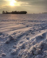 Scenic view of frozen landscape against sky during sunset