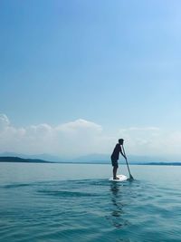Man paddleboarding in sea against sky