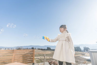 Portrait of young woman standing against clear sky