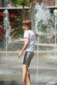Full length of smiling boy splashing water
