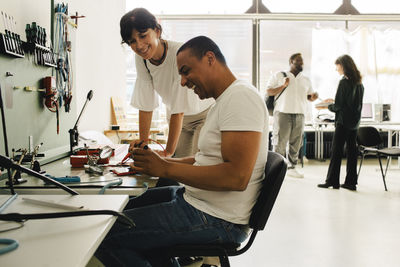 Female customer standing near happy male technician repairing smart phone at store