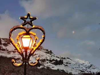 Close-up of illuminated light bulb against sky