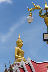Low angle view of statue by building against sky