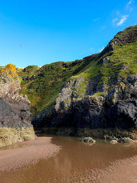 Scenic view of sandy beach and coastal cliffs against sky