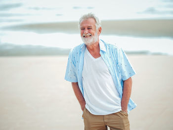 Smiling mature man standing at beach