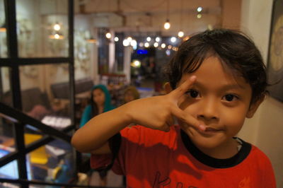 Portrait of cute boy showing peace sign in restaurant