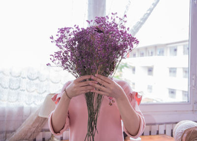 Low angle view of woman holding pink flowering plant