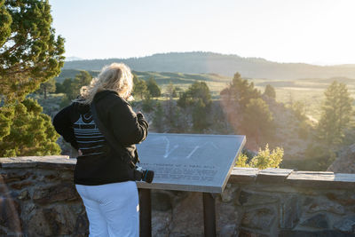 Rear view of woman standing by wall against landscape