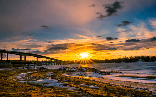 Bridge over sea against sky during sunset