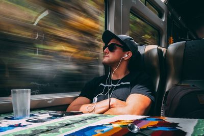 Young man listening music through headphones in train