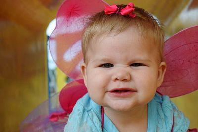 Close-up portrait of cute baby girl wearing wings dressed as angel