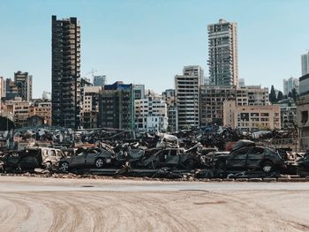 Stack of cars destroyed by the beirut explosion in front of damaged buildings in city against sky