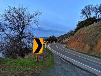 Directional road signs for curve on mountain highway. lake water in background.