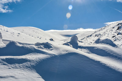 Scenic view of snowcapped mountains against blue sky