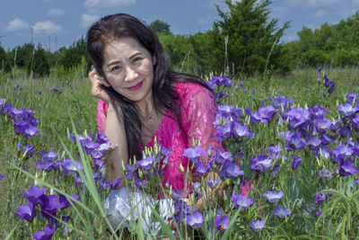 Portrait of smiling young woman with purple flowers in field