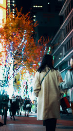 Rear view of people walking on city street at night