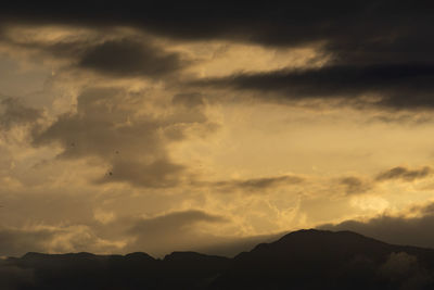 Low angle view of silhouette mountains against dramatic sky