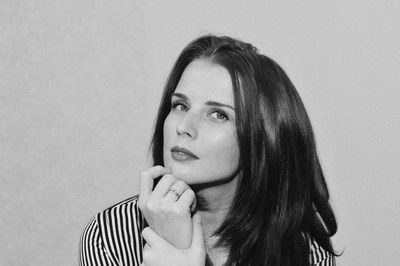 Portrait of young woman looking away against white background