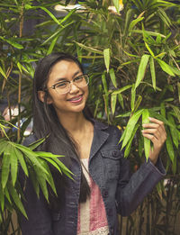 Portrait of smiling young woman standing by plants