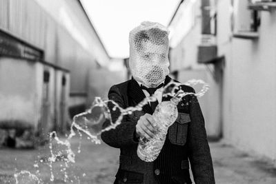 Midsection of man holding a bottle of water with bubble wrap covering his face 