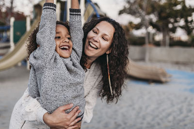 Close up of happy son and mother playing outside on playground at dusk