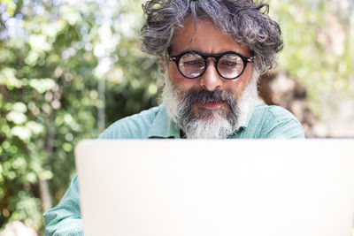 Portrait of a man with gray hair and a beard working on the laptop person