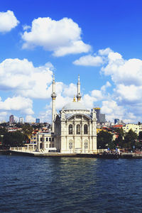 Ortakoy mosque by river against sky