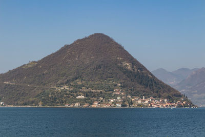 Scenic view of sea and mountains against clear blue sky