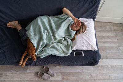 High angle view of woman with dog lying on sofa