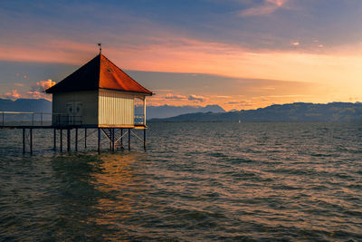 Lifeguard hut by sea against sky during sunset