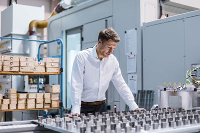 Businessman in factory looking at machine