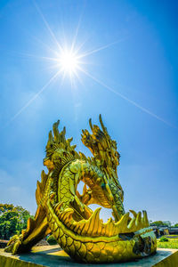 Low angle view of dragon statue against blue sky