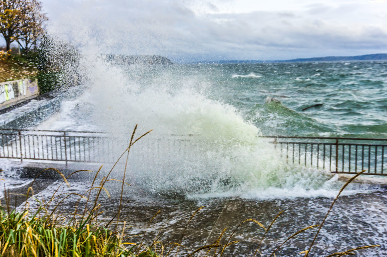 water, motion, shore, sea, wave, power in nature, splashing, nature, coast, beauty in nature, sports, breaking, water sports, no people, body of water, day, sky, outdoors, ocean, scenics - nature, beach, land, cloud, hitting, railing