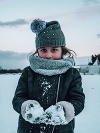 Portrait of girl in warm clothing holding snow during winter