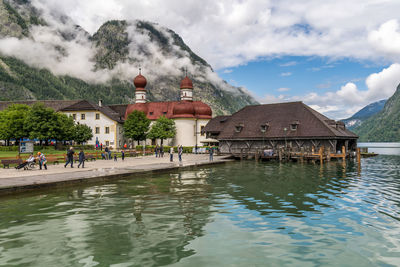 Buildings at waterfront against cloudy sky